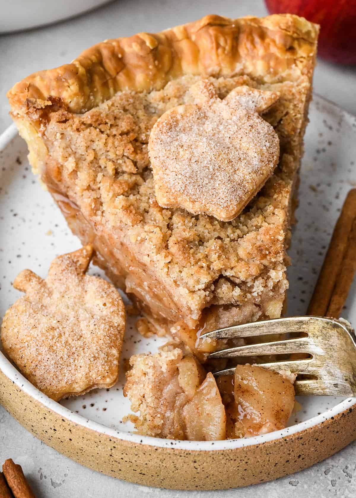 a fork taking a bite of a slice of apple crumb pie on a plate 