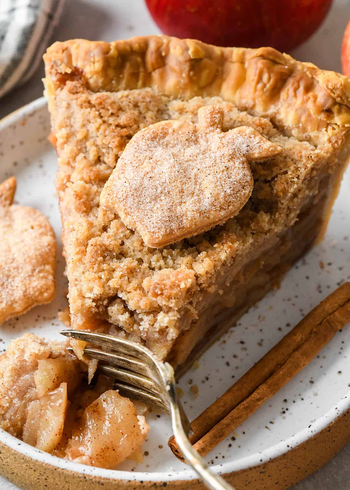 a slice of apple crumb pie on a plate with a fork taking a bite