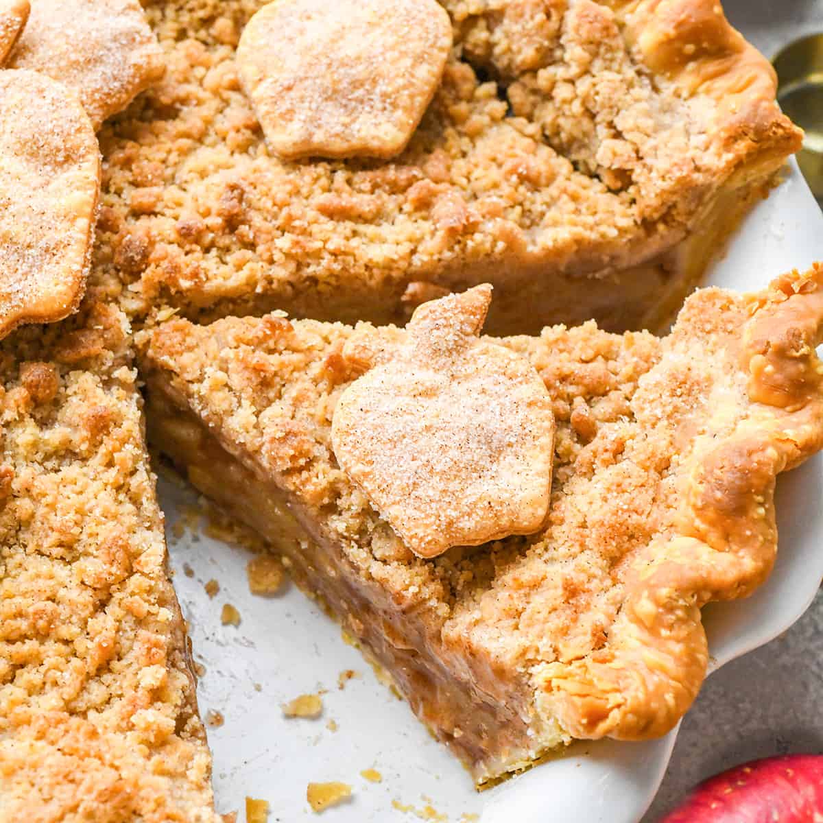 apple crumb pie in a pie dish with a piece cut out