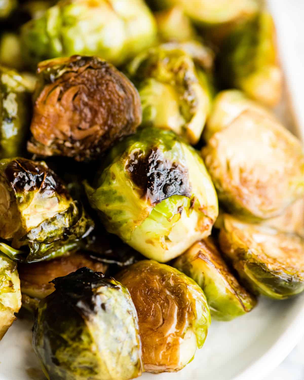 up close front view of balsamic roasted brussel sprouts on a serving dish