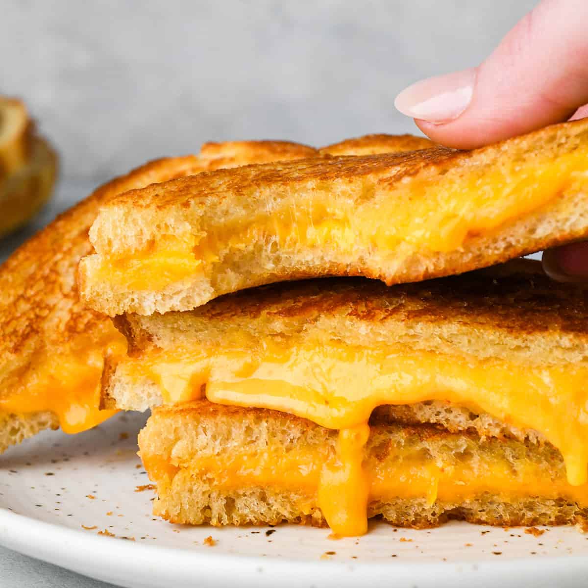 a stack of three halves of grilled cheese sandwiches, the top one with a bite taken out of it