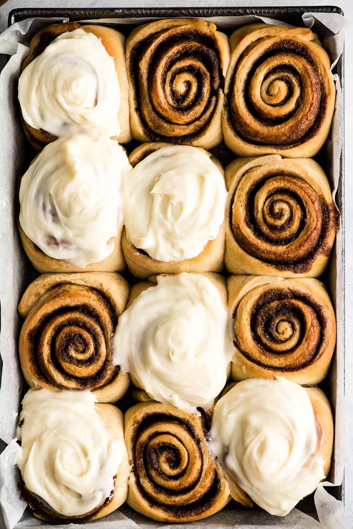 overhead view of a pan of 12 homemade cinnamon rolls with cream cheese frosting