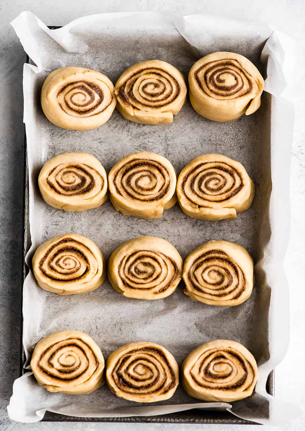 Overhead photo showing how to make cinnamon rolls - rolls in baking pan before rising
