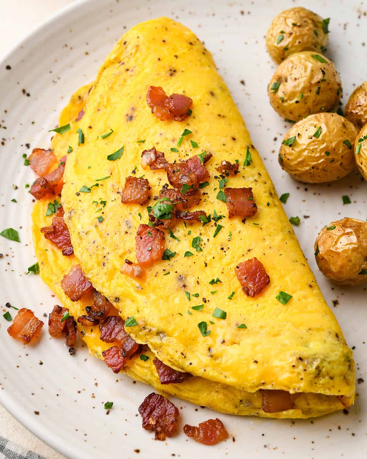 an omelette with bacon, herbs and a  side of potatoes. 