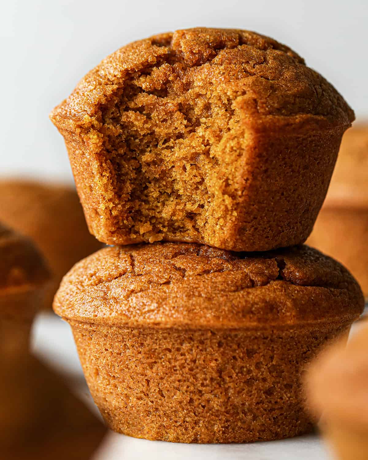 a stack of two Pumpkin Muffins, the top one has a bite taken out of it