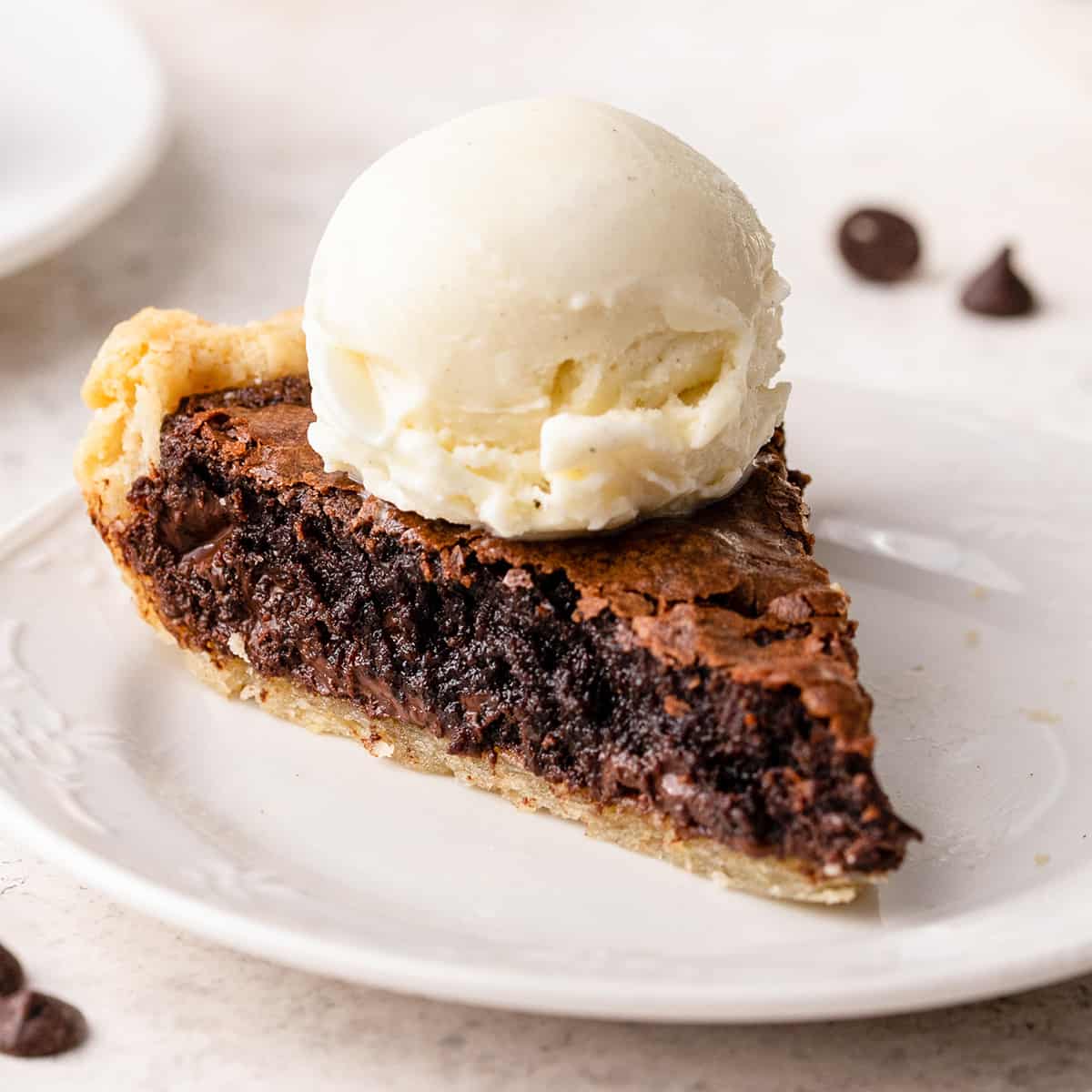 a slice of brownie pie on a plate topped with vanilla ice cream
