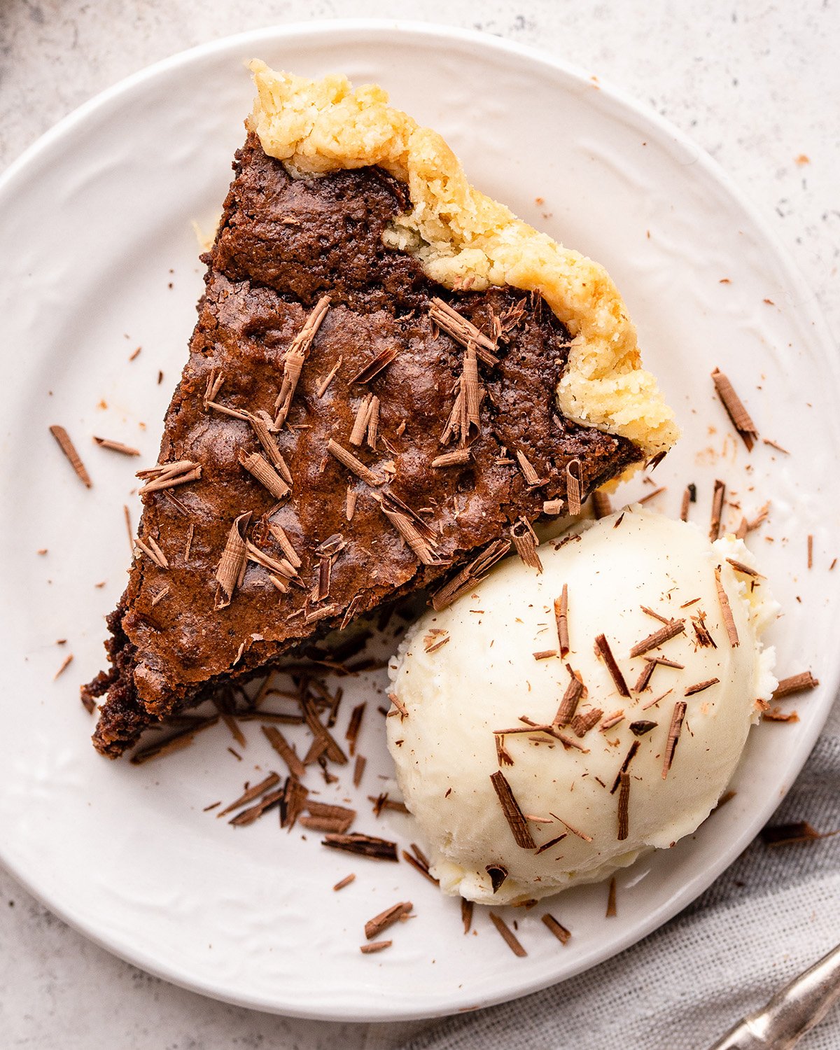 a piece of Brownie Pie on a plate with ice cream and chocolate shavings