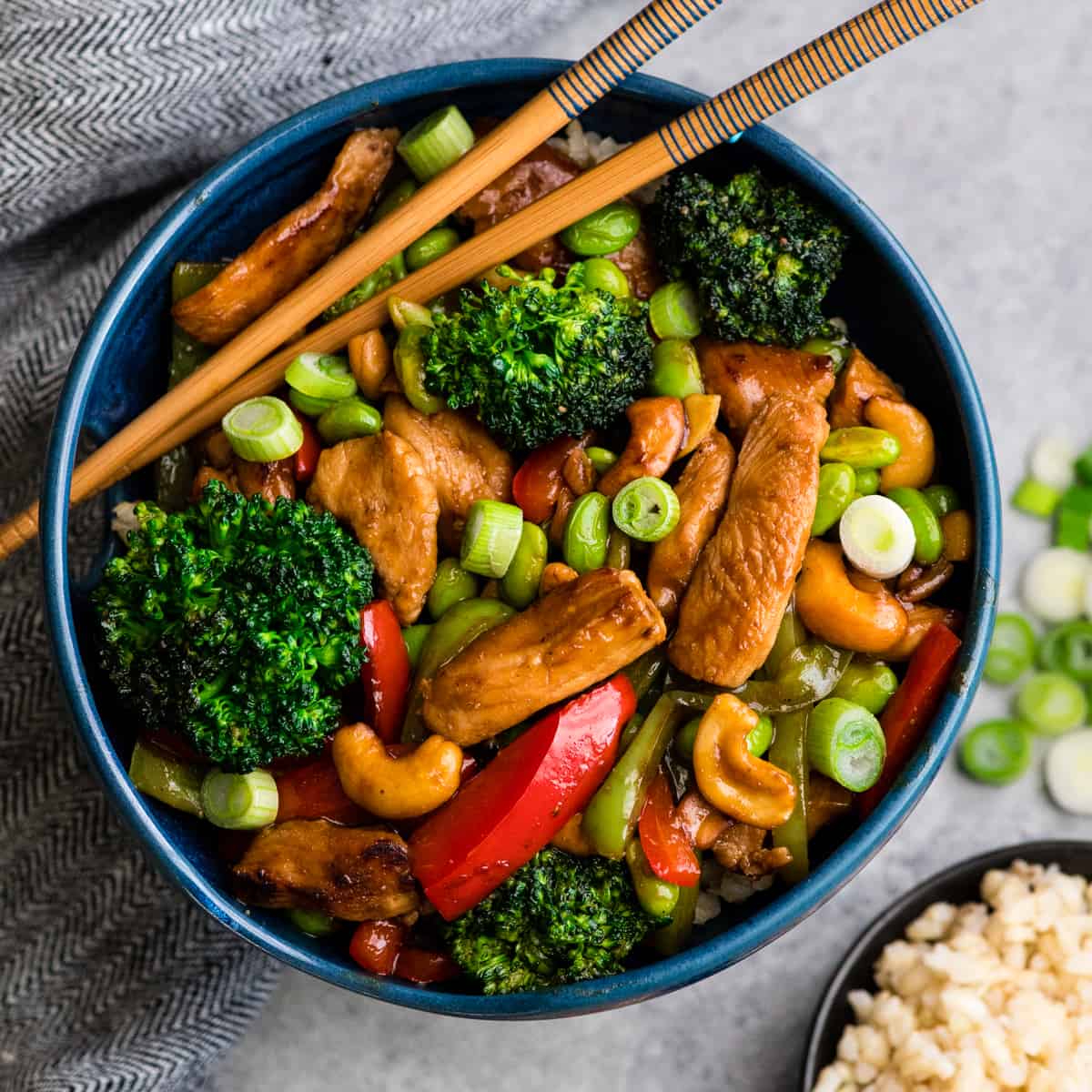 Overhead view of Cashew Chicken Stir Fry Recipe in a blue bowl with chopsticks 