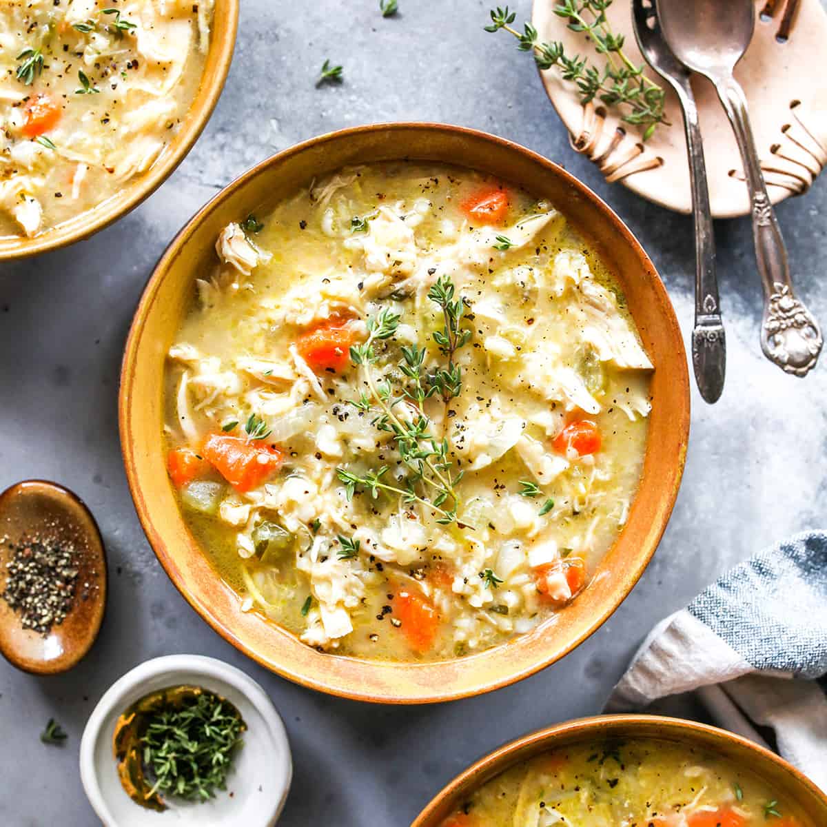 overhead view of a bowl of chicken and rice soup with fresh herbs