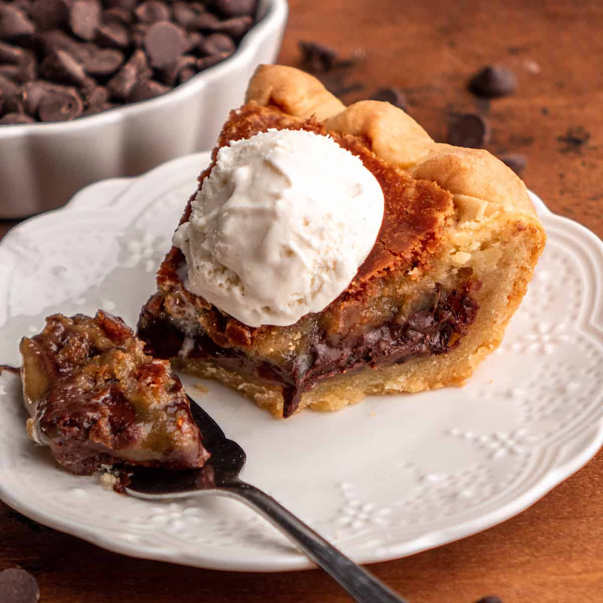 a fork taking a bite of Chocolate Chip Cookie Pie on a plate with vanilla ice cream