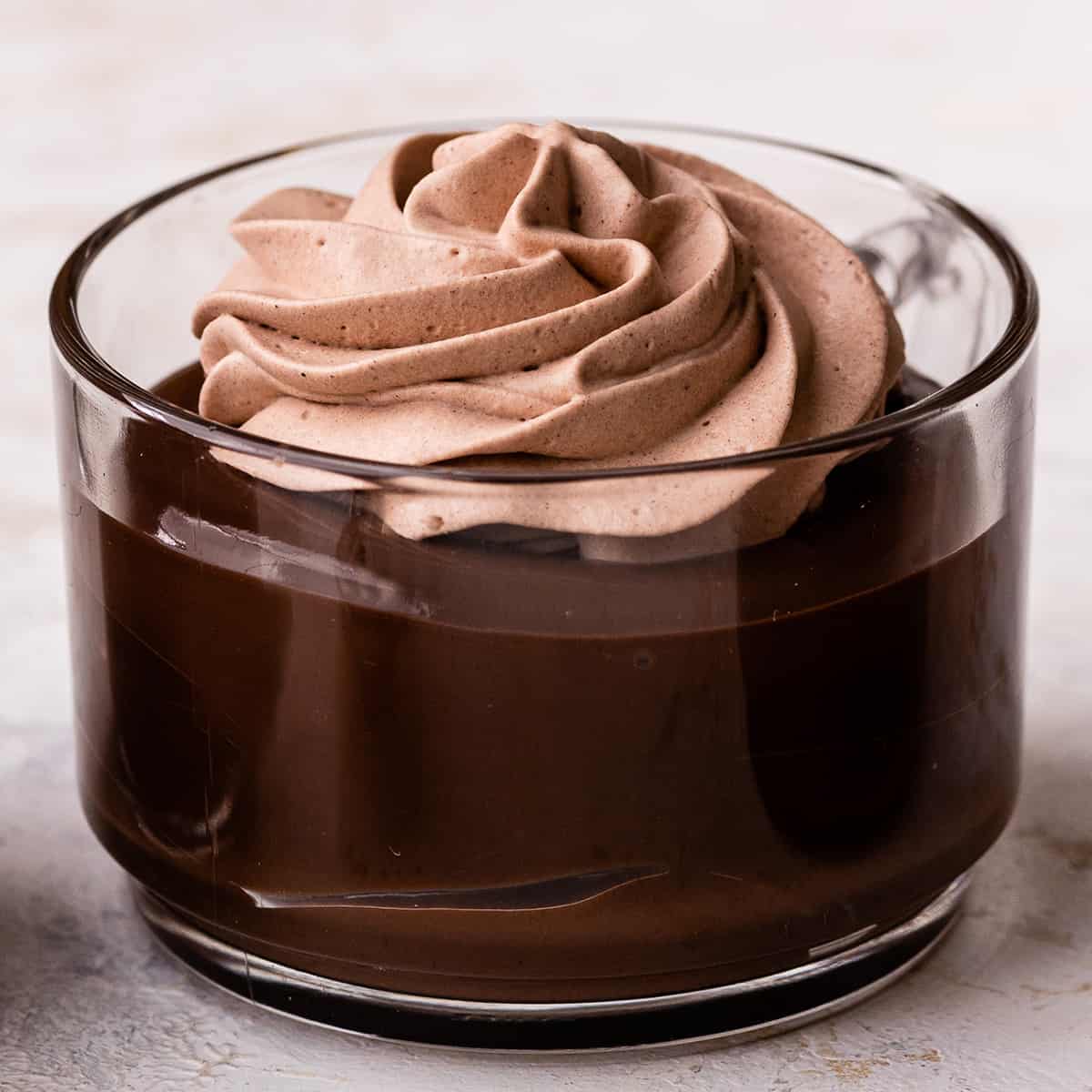 Chocolate Whipped Cream piped onto chocolate pudding in a glass cup