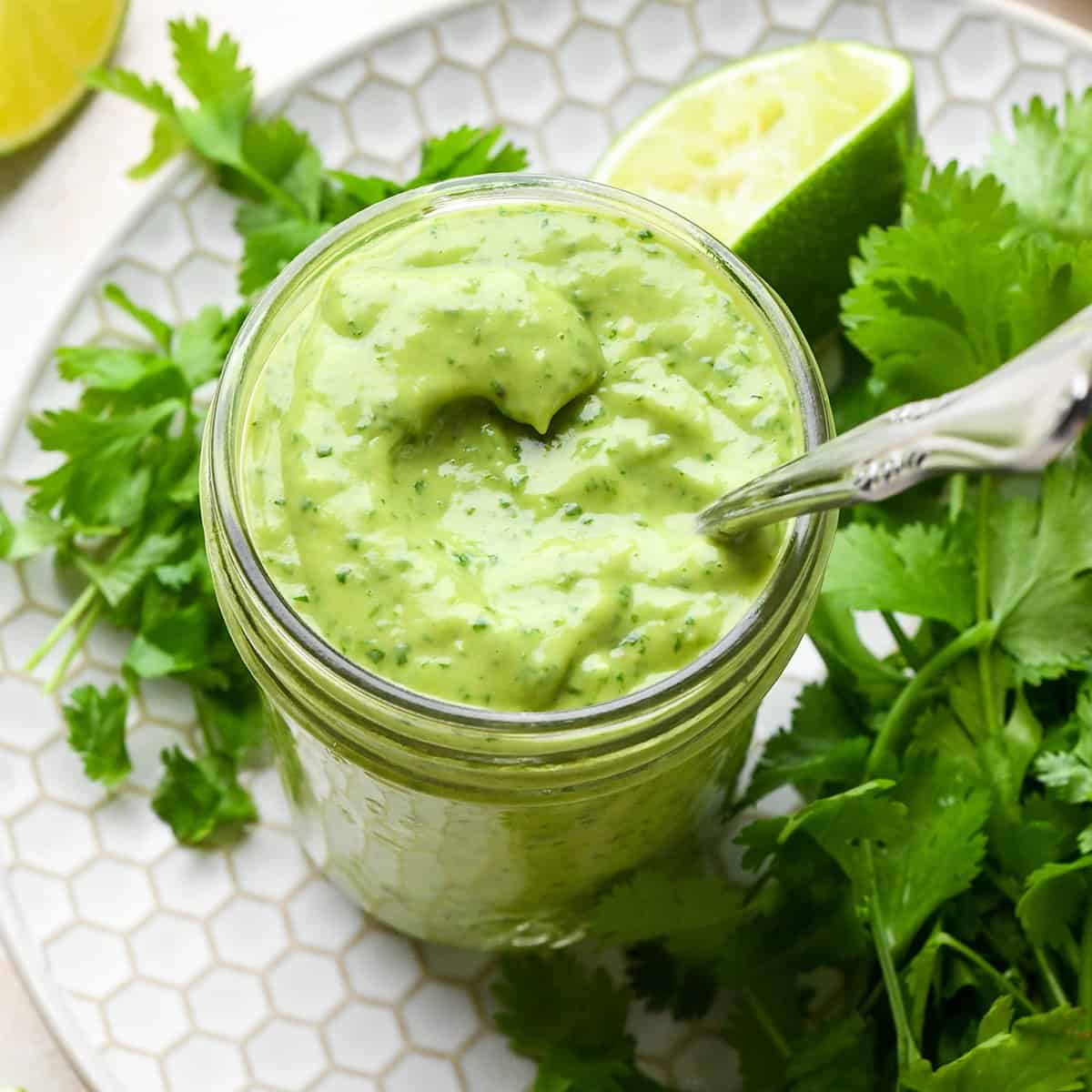 a jar of Cilantro Lime Avocado Dressing with a spoon in it