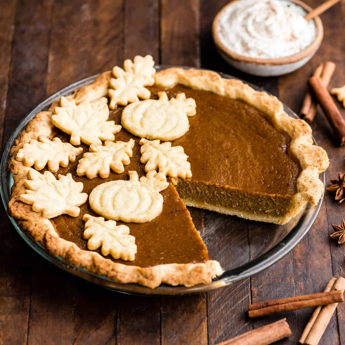overhead front view of a dairy-free pumpkin pie in a glass pie dish with one slice removed
