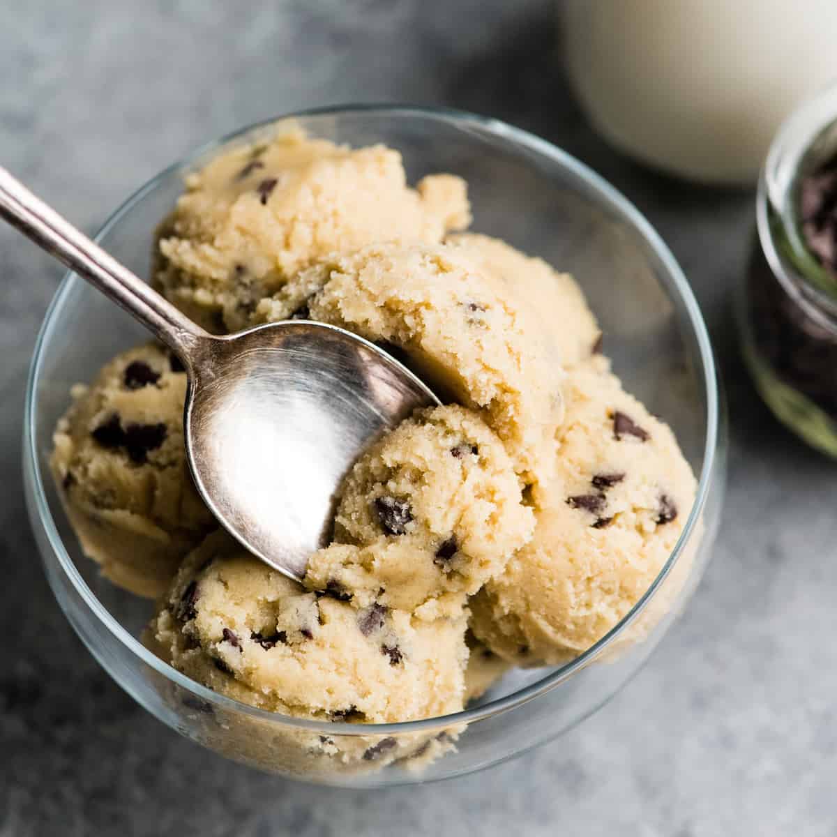 up close overhead view of a spoonful of Edible Cookie Dough resting on the rest of the cookie dough in a glass dish