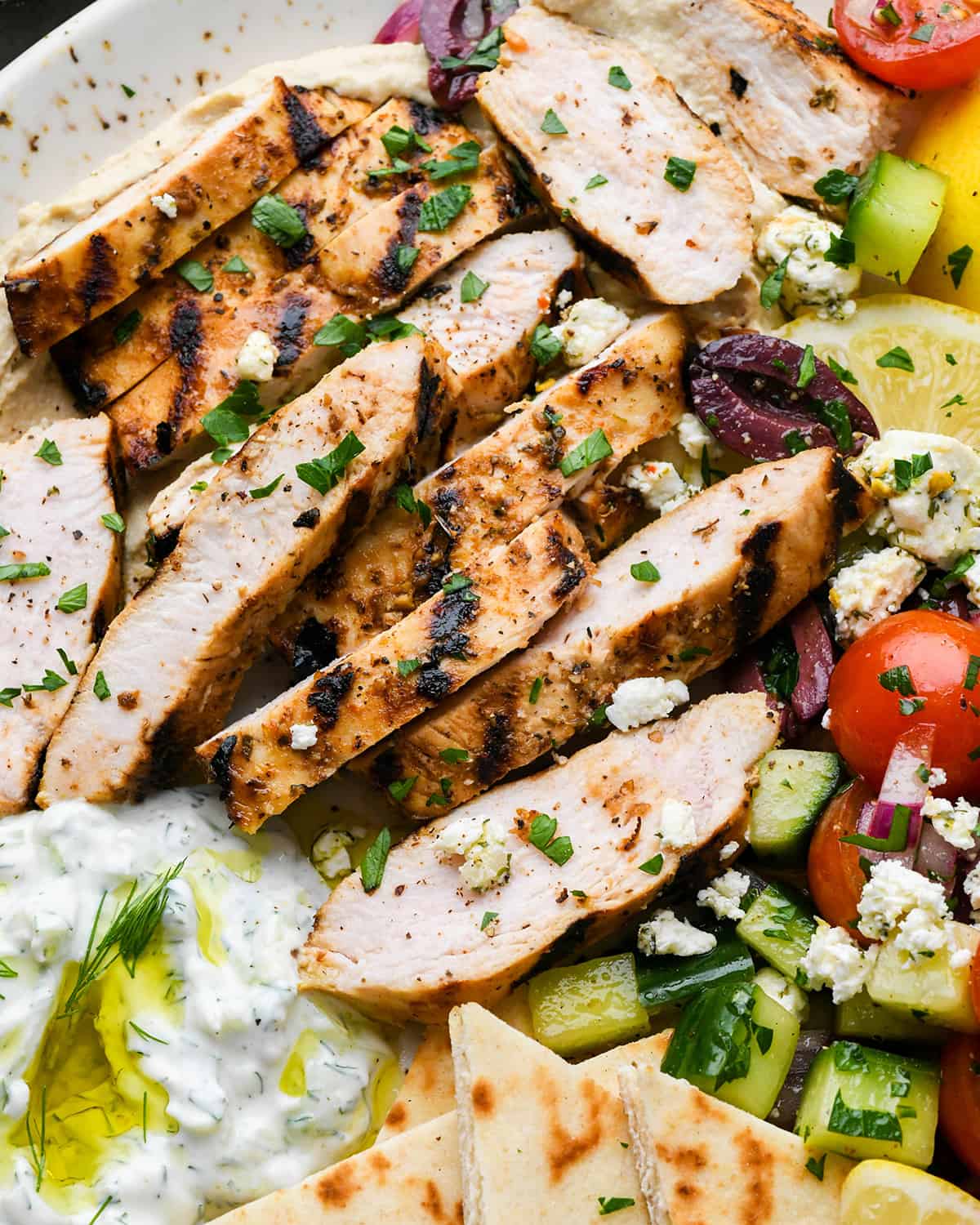 Greek Chicken cut into strips on top of a greek salad