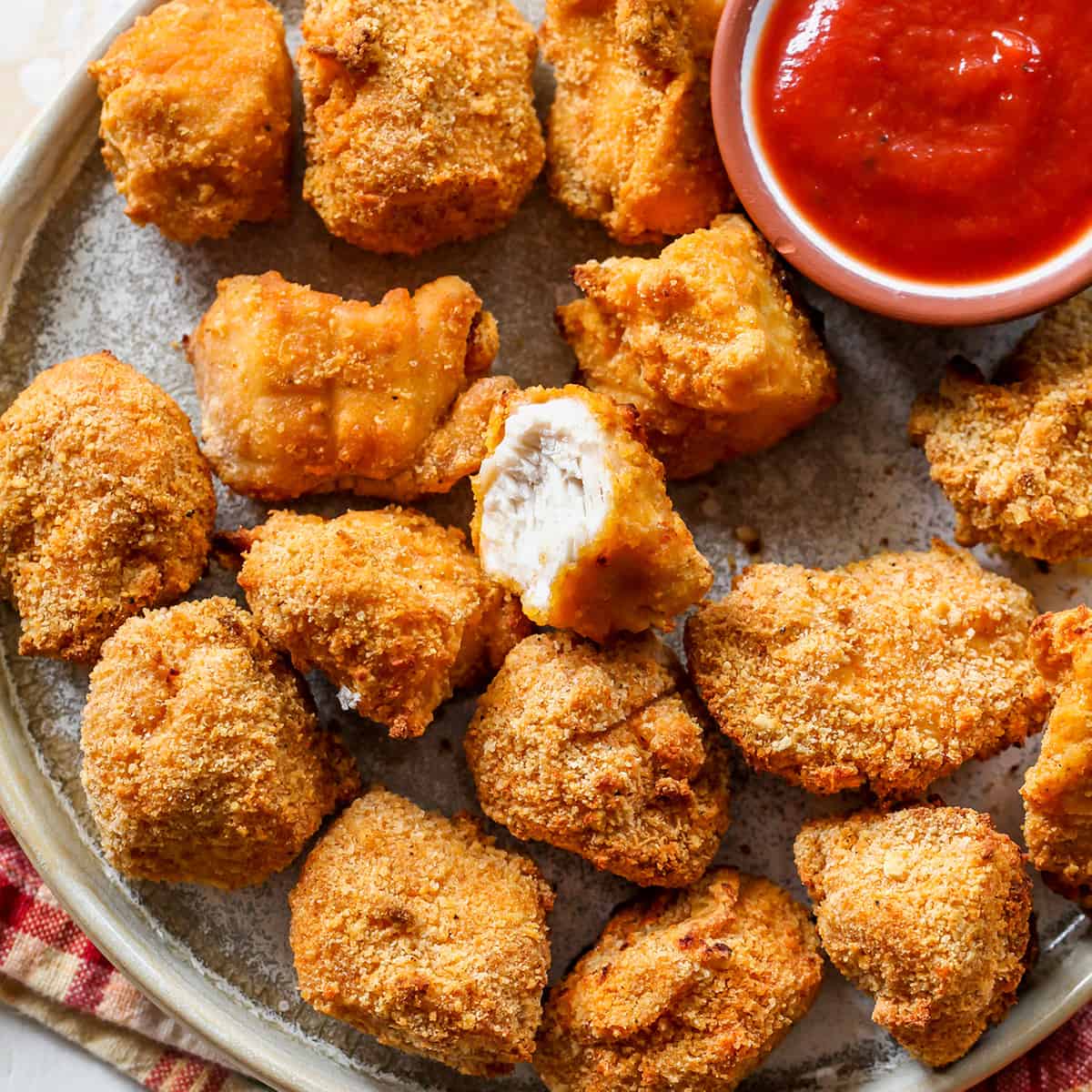 overhead view of Homemade Chicken Nuggets on a plate, one has a bite taken out of it