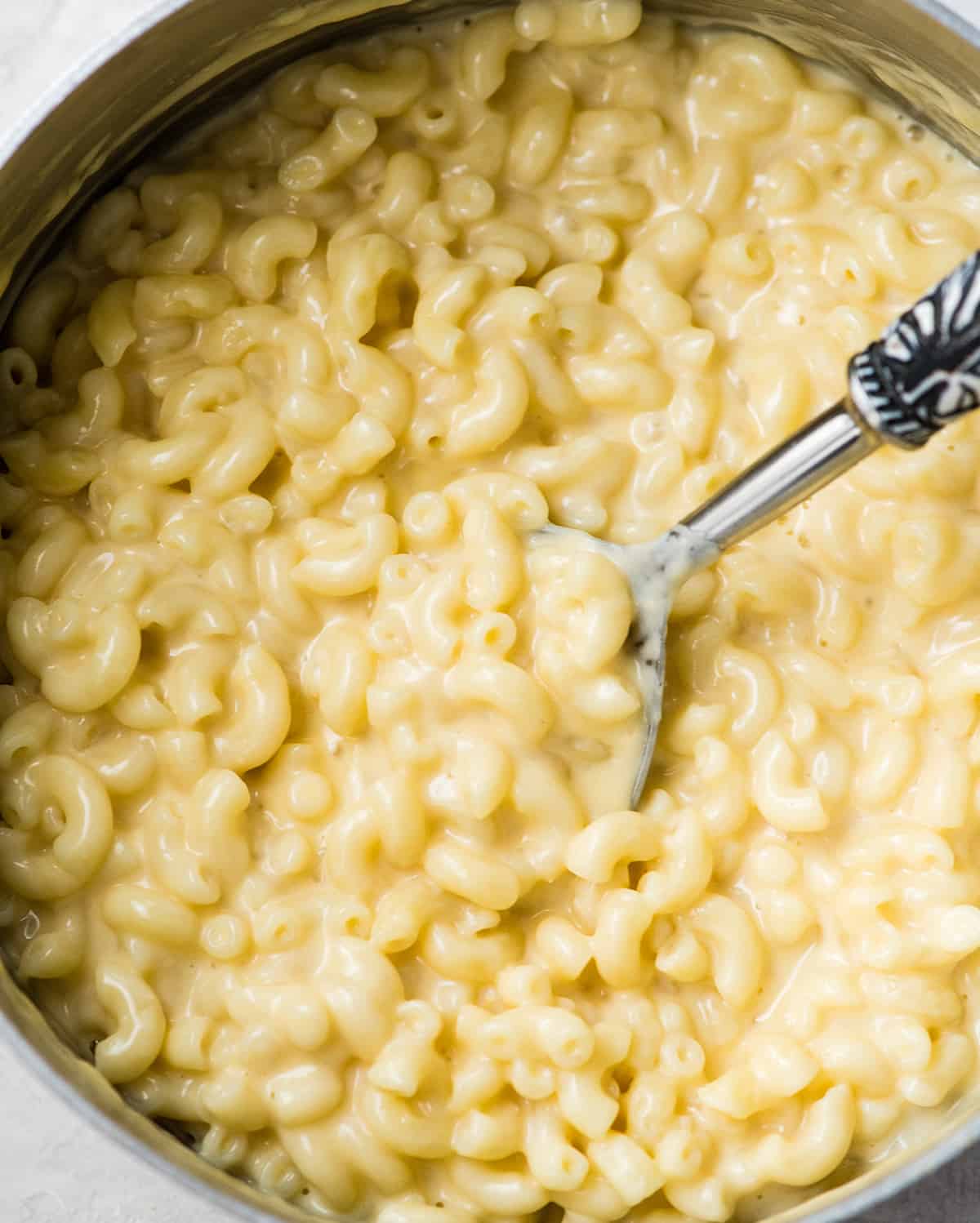 overhead photo of homemade mac and cheese in a pot with a spoon taking a scoop