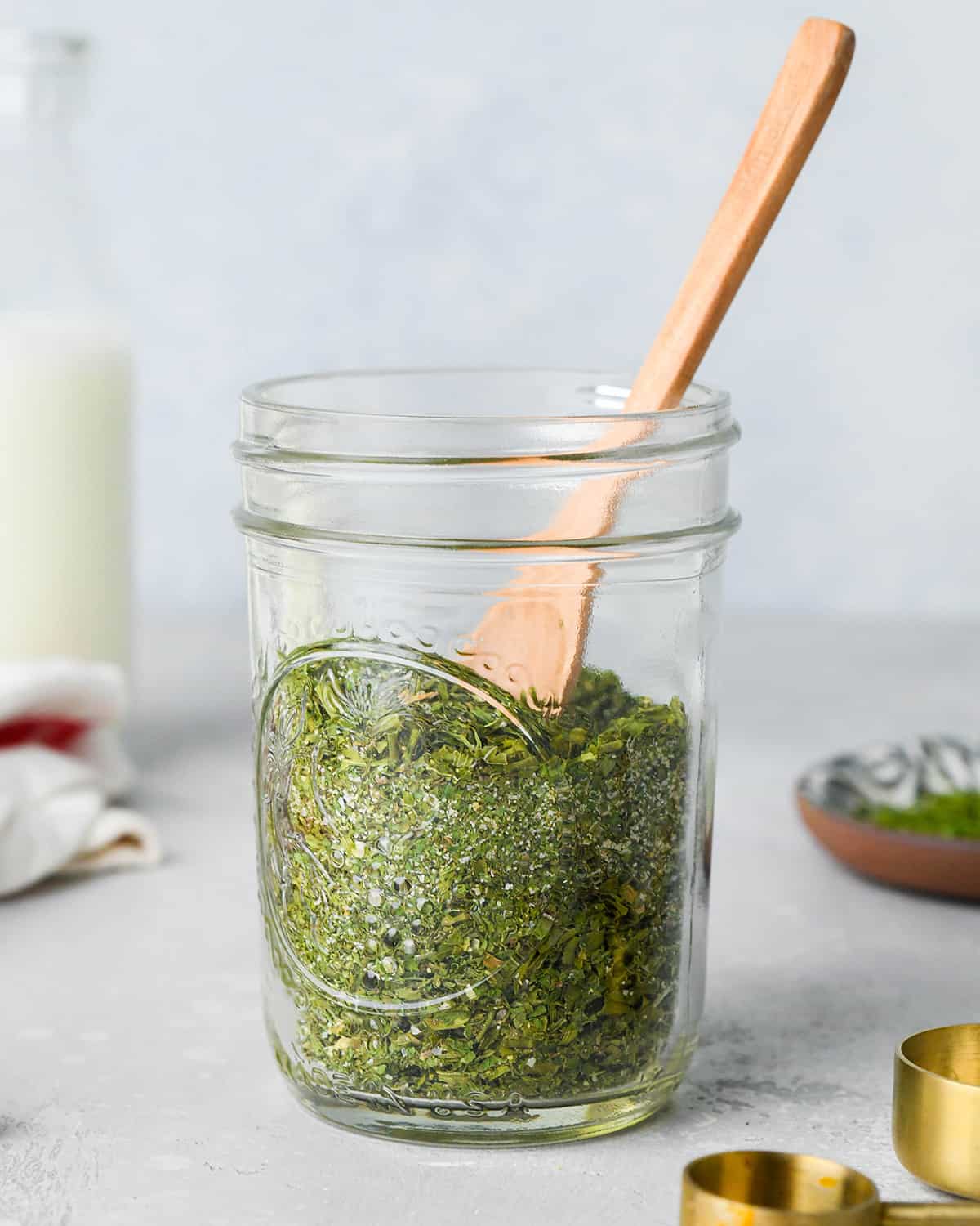 glass jar of Ranch Dressing Mix with a wooden spoon inside