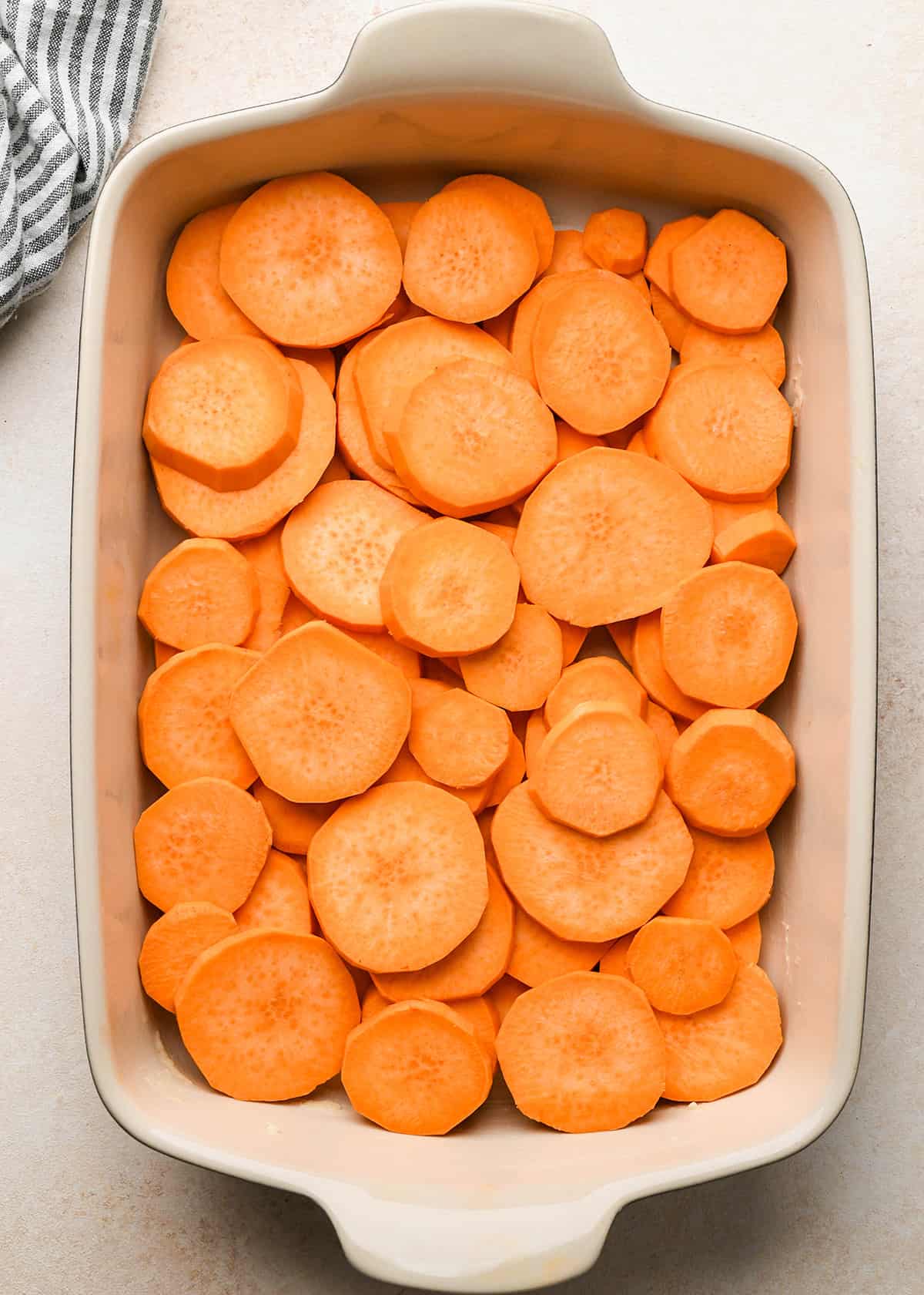 round sweet potato slices arranged in layers in a baking dish to make candied yams