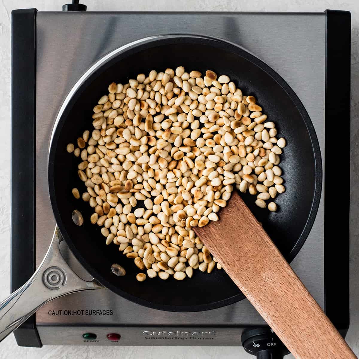 overhead view of toasting pine nuts in a small pan