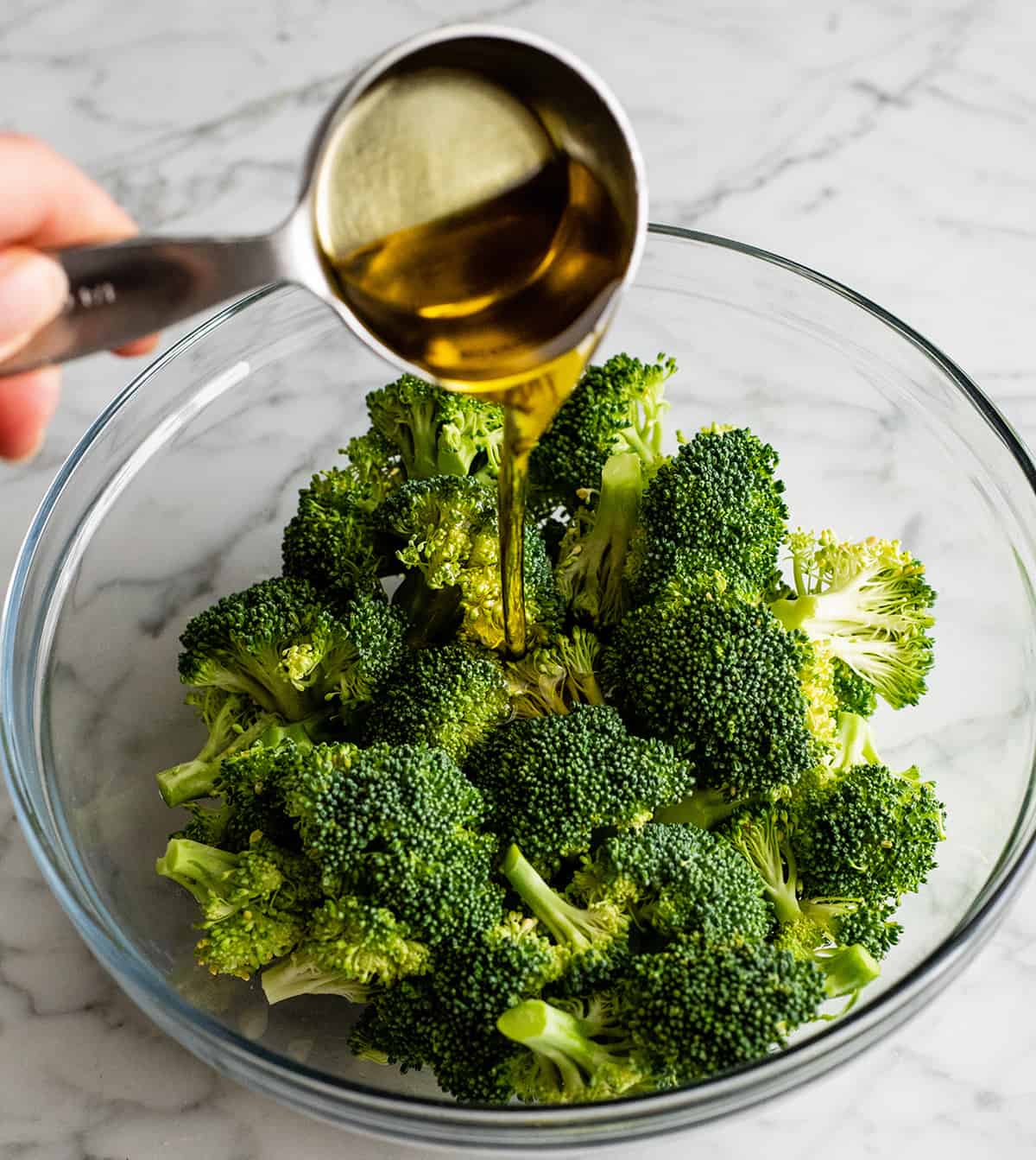 photo showing how to roast broccoli - pouring olive oil over broccoli
