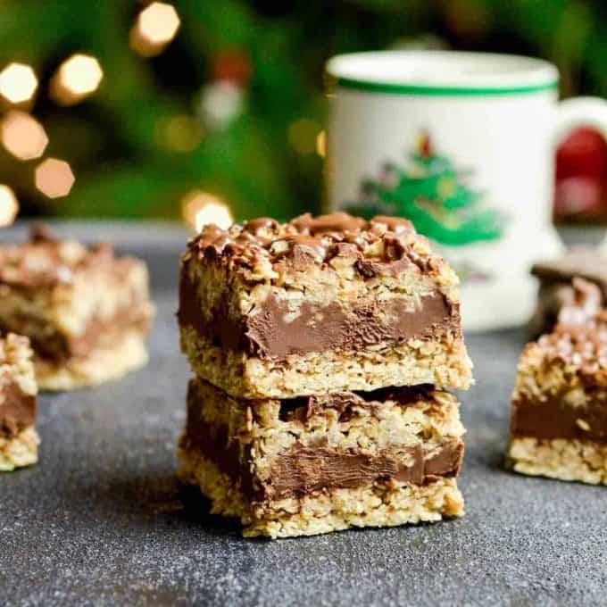 Front view of two No-Bake Chocolate Peanut Butter Oatmeal Bars stacked on each other with a Christmas tree in the background