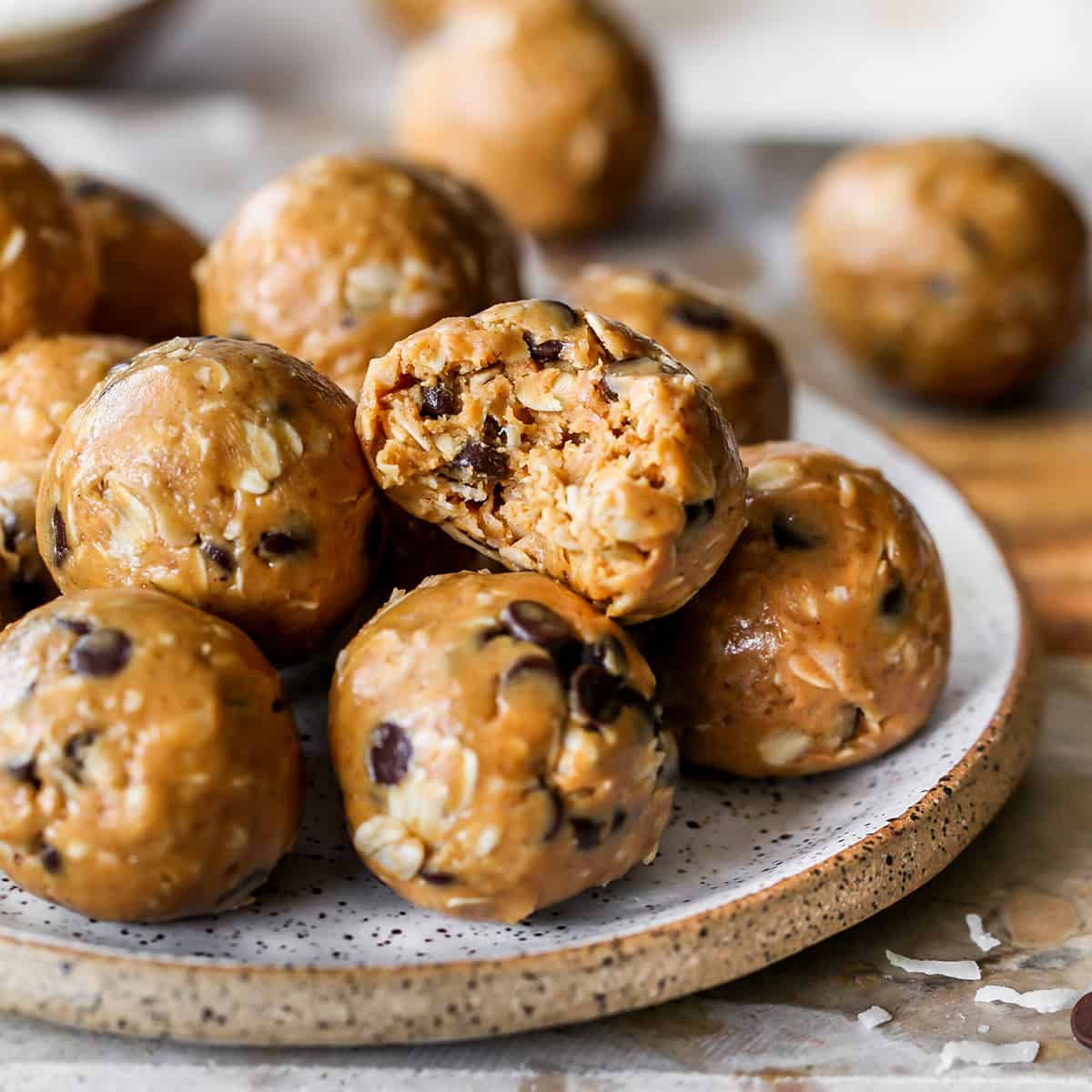 8 peanut butter protein balls stacked on a plate, the top one has a bite taken out of it