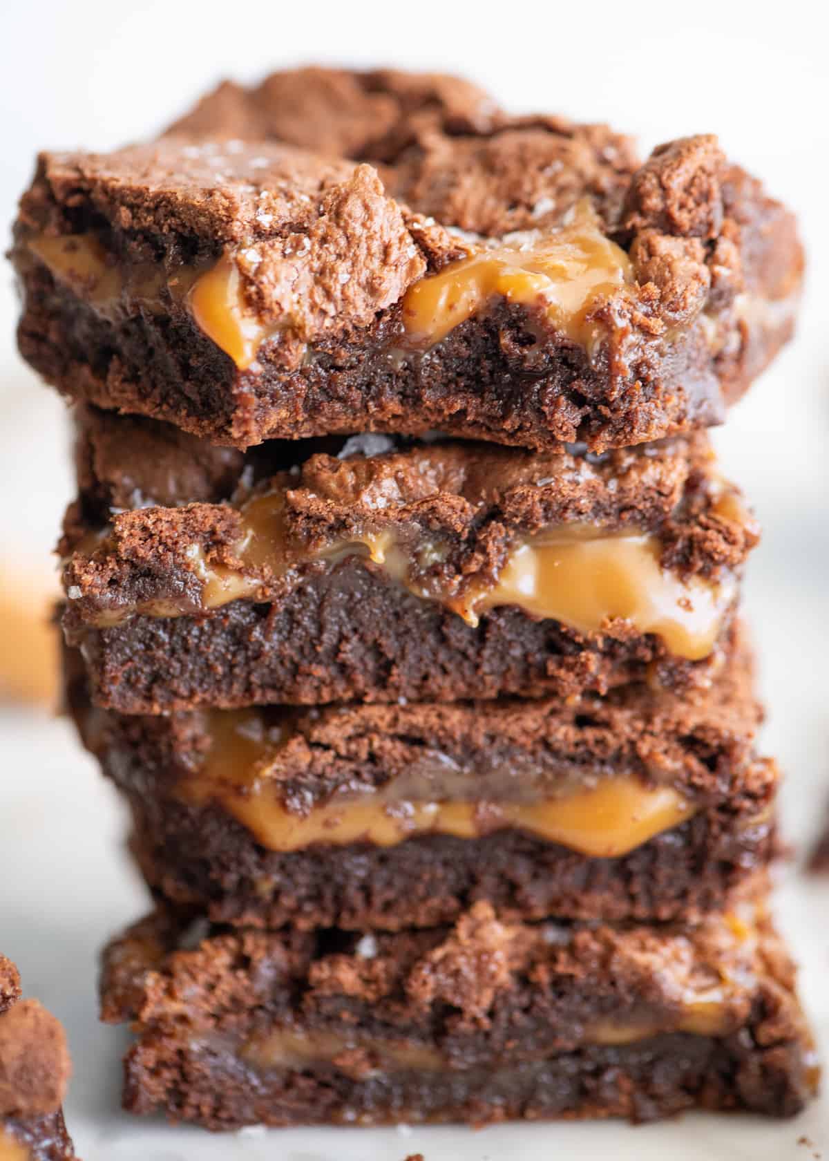 stack of 4 salted caramel brownies, the tope one has a bite taken out of it