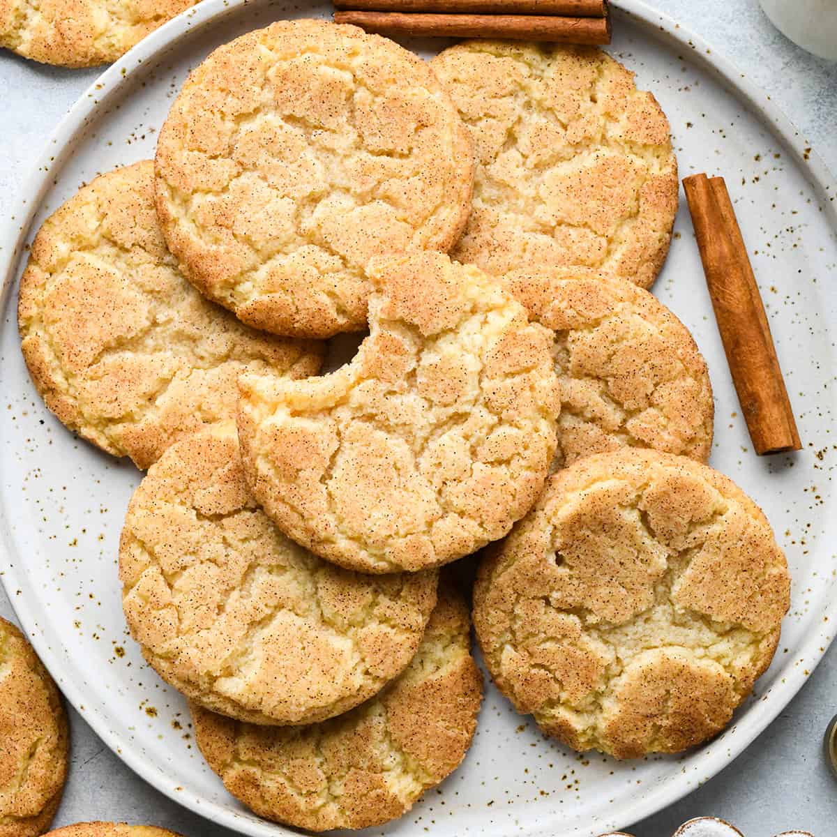 8 snickerdoodle cookies on a plate, one has a bite taken out of it